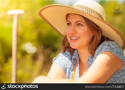 Portrait of mature smiling woman wearing big straw hat in garden