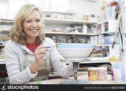 Portrait Of Mature Woman Decorating Bowl In Pottery Class