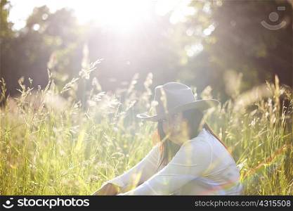 Portrait of mature woman in long grass wearing cowboy hat