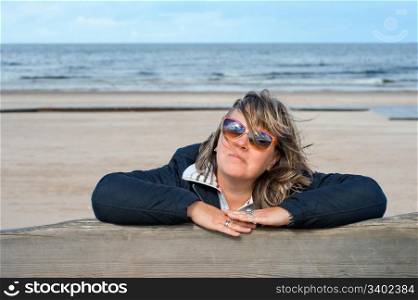 Portrait of mature woman in sunglasses relaxing at the Baltic sea in autumn day.