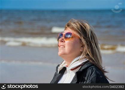 Portrait of mature woman in sunglasses relaxing at the Baltic sea in autumn day.