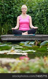 Portrait Of Mature Woman In Yoga Position On Wooden Jetty By Lake