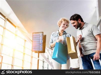 Portrait of mature woman showing present she bought in duty free with her husband at airport