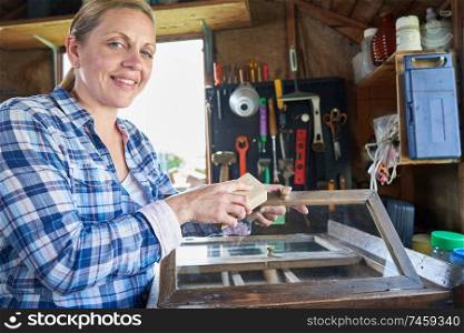 Portrait Of Mature Woman Upcycling Furniture In Workshop At Home