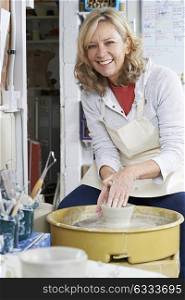 Portrait Of Mature Woman Working At Potters Wheel In Studio