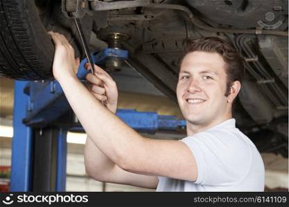 Portrait Of Mechanic Working On Wheel Underneath Car