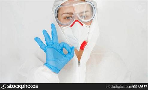 Portrait of medical worker or doctor protecting with suit and mask from covid-19 showing OK sign with fingers. Global pandemic and lockdown.. Portrait of medical worker or doctor protecting with suit and mask from covid-19 showing OK sign with fingers. Global pandemic and lockdown