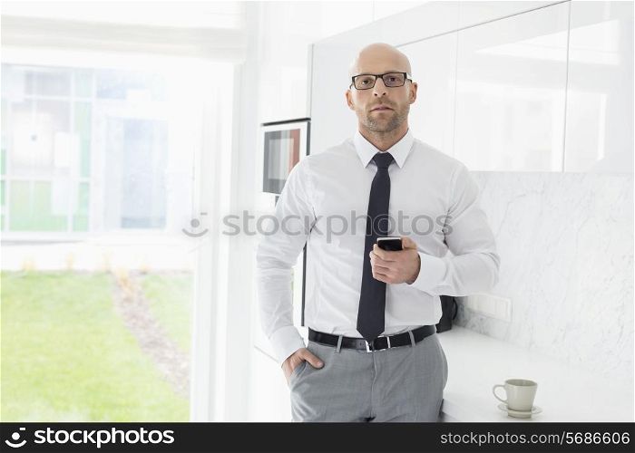 Portrait of mid adult businessman holding smart phone at home