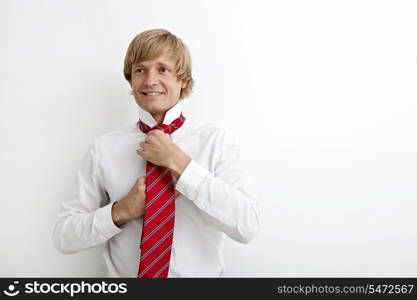 Portrait of mid adult businessman tying tie against white background