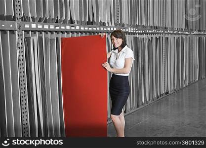 Portrait of mid adult businesswoman holding thin red veneer sheet