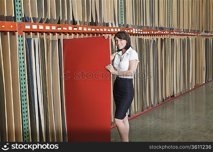 Portrait of mid adult businesswoman holding thin red veneer sheet