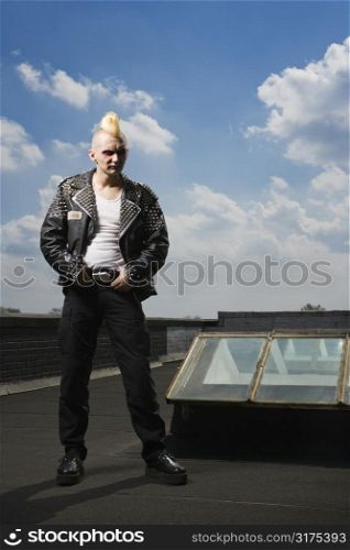 Portrait of mid-adult Caucasian male punk standing on roof.