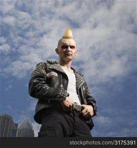 Portrait of mid-adult Caucasian male punk with skyline in background.