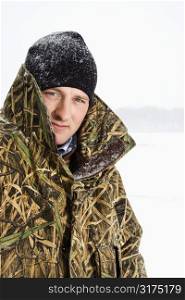 Portrait of mid-adult Caucasian male wearing camouflage jacket and beanie on frozen Green Lake, Minnesota.
