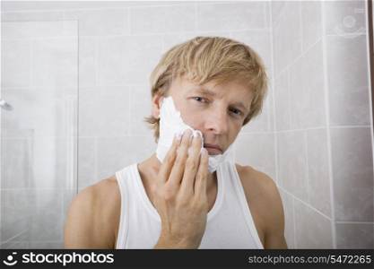 Portrait of mid-adult man applying shaving cream in bathroom