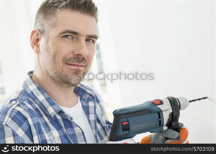 Portrait of mid-adult man drilling hole in wall