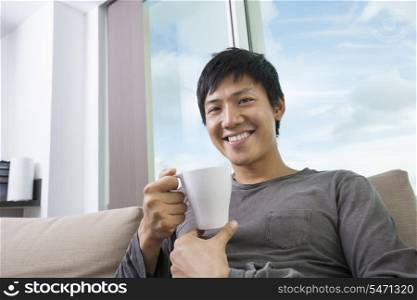 Portrait of mid adult man holding coffee cup in house