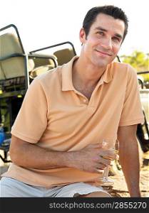 Portrait of mid-adult man holding wineglass smiling jeep in background