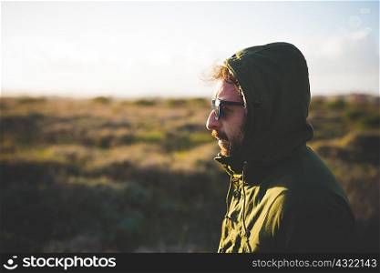 Portrait of mid adult man wearing anorak hood in field