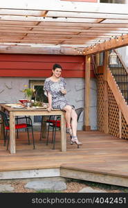 Portrait of mid adult woman sitting on patio table