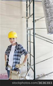 Portrait of mid adult woman standing with hands on hips at construction site