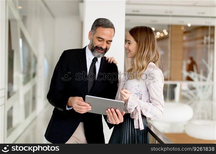 Portrait of middle-aged businessman and young businesswoman with tablet in offfice