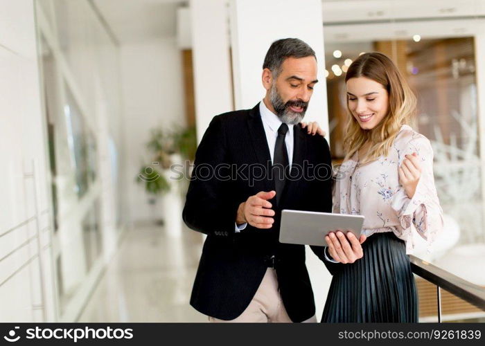 Portrait of middle-aged businessman and young businesswoman with tablet in offfice