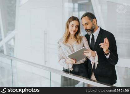 Portrait of middle-aged businessman and young businesswoman with tablet in offfice