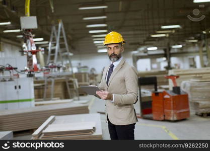 Portrait of middle-aged businessman with digital tablet in factory