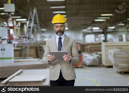 Portrait of middle-aged businessman with digital tablet in factory