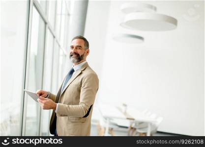 Portrait of middle aged  businessman with tablet in office