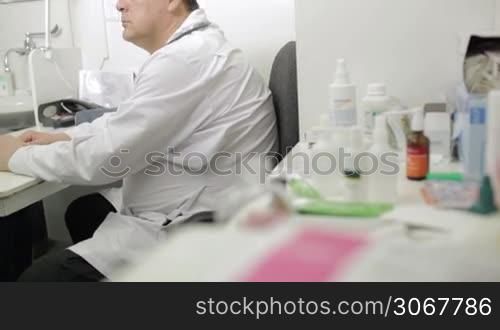 Portrait of middle-aged doctor in lab coat with stethoscope looking to the photographer