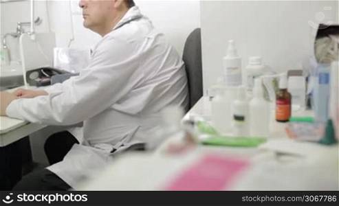 Portrait of middle-aged doctor in lab coat with stethoscope looking to the photographer