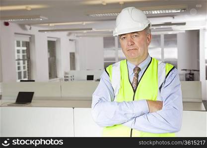 Portrait of middle-aged man in reflector vest and hard hat at office