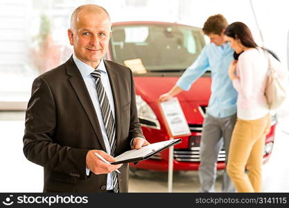 Portrait of middle aged salesman in car retail store