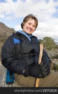 Portrait of middle-aged woman holding hiking pole and smiling
