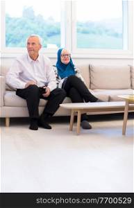 portrait of modern muslim senior couple sitting on the sofa before iftar dinner during a ramadan feast at home