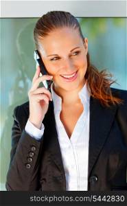 Portrait of modern smiling business woman talking on mobile at office building &#xA;
