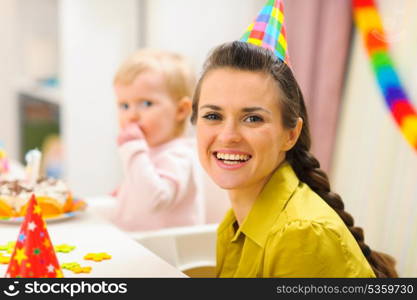 Portrait of mother and baby eating birthday cake in background