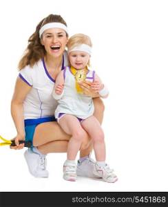Portrait of mother and baby in tennis clothes holding medal