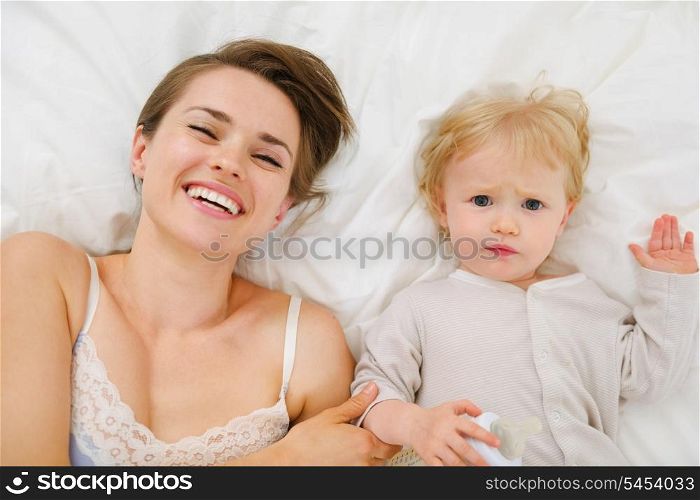 Portrait of mother and baby laying in bed. Upper view