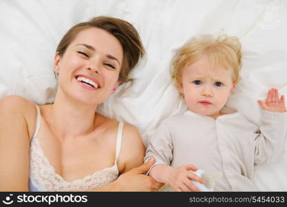 Portrait of mother and baby laying in bed. Upper view