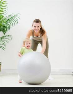 Portrait of mother and baby playing with fitness ball