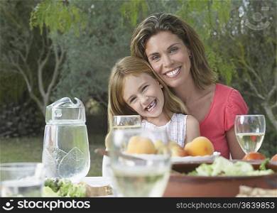 Portrait of mother and daughter (5-6) at garden table