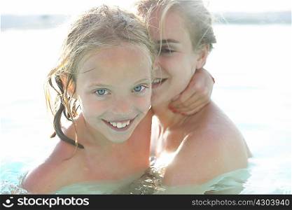 Portrait of mother and daughter in outdoor swimming pool