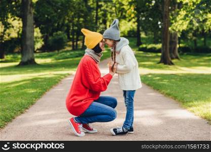 Portrait of mother and daughter keep noses closely to each other, enjoy calm atmosphere, have understanding between each other. Adorable child loves her mom greatly. Closeness concept