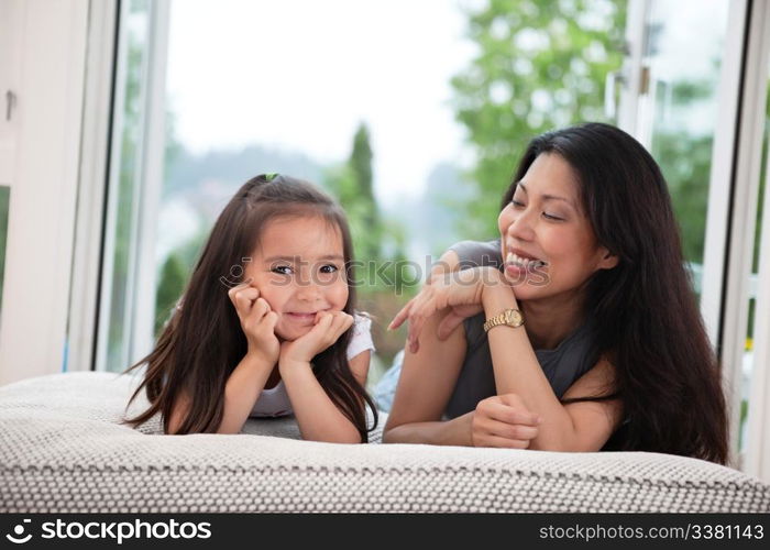 Portrait of mother and daughter lying on couch