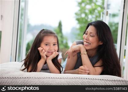 Portrait of mother and daughter lying on couch