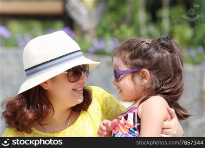 Portrait of mother and daughter outdoors looking each other in sumertime. Focus on the little girl