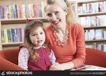 Portrait Of Mother And Daughter Reading Book In Library